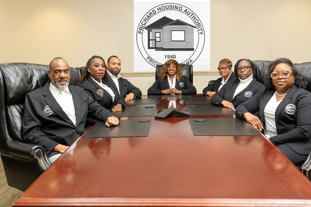 Prichard Housing Authority CEO and Executive Team sit around the board table smiling at the camera